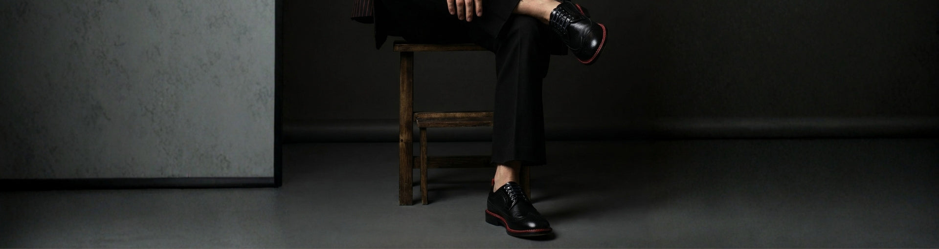 Close-up of Pintta Dublin Black shoes with red welt in dark setting, expressing bold presence and quiet luxury