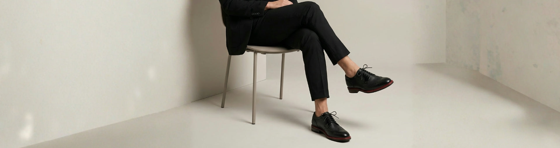 Man wearing Pintta Dublin Black shoes with black suit, seated, showcasing quiet luxury footwear and European craftsmanship